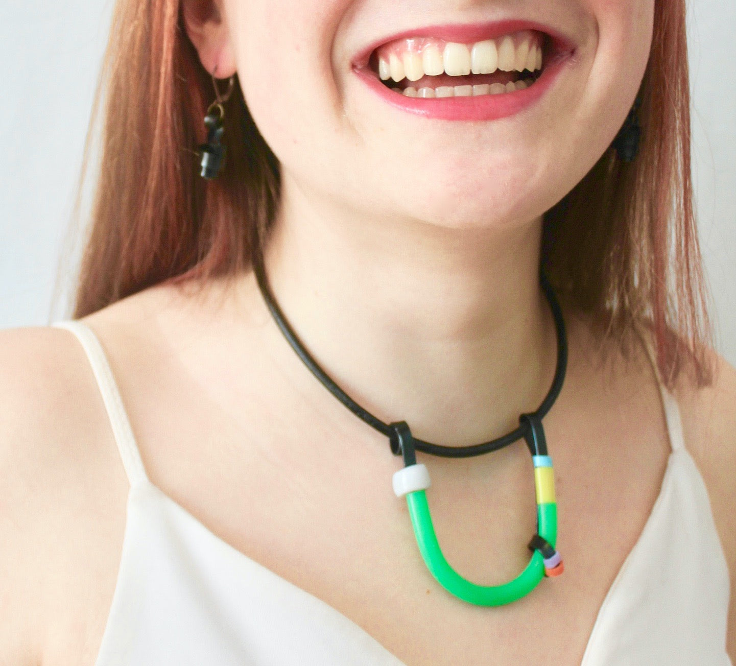 Sadye is wearing the Black with Green, White and Colours Uline on a fine leather cord that hangs 40cm with black Loopt earrings.