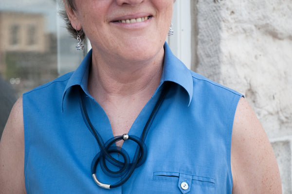 Hazel is wearing Loopt earrings in round silver and a navy Tubular necklace