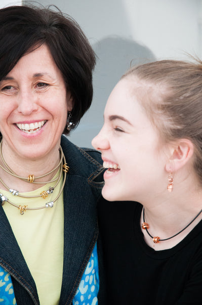 Helga is wearing a 170cm long Loopt in beige with mixed metal and Avery is wearing flat copper Loopt earrings with a thin copper Rubber Loopt.