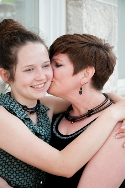 Shelly is adorning flat Loopt earrings in black. Shelly is also wearing a netted Loopt necklace in gold and black. Olivia is wearing a fine Loopt necklace/bracelet.