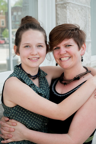 Shelly is adorning flat Loopt earrings in black. Shelly is also wearing a netted Loopt necklace in gold and black. Olivia is wearing a fine Loopt necklace/bracelet.