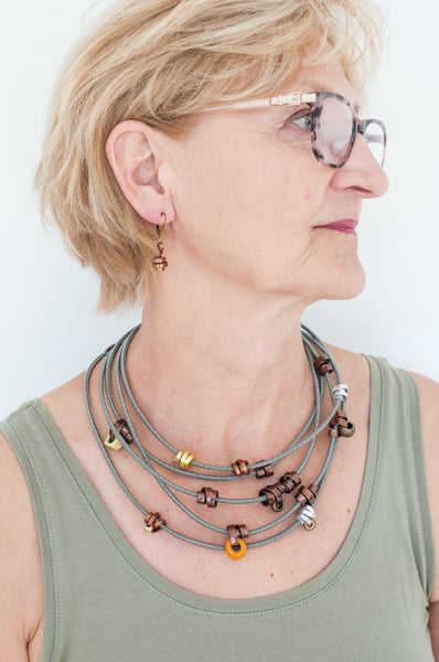 Beverly is wearing 2 112cm Loopt necklaces. Both in fine taupe cord. One with flat bronze wire and mixed neutral coloured beads and the other in mixed thin wire. Beverly is also wearing thin bronze Loopt earrings.