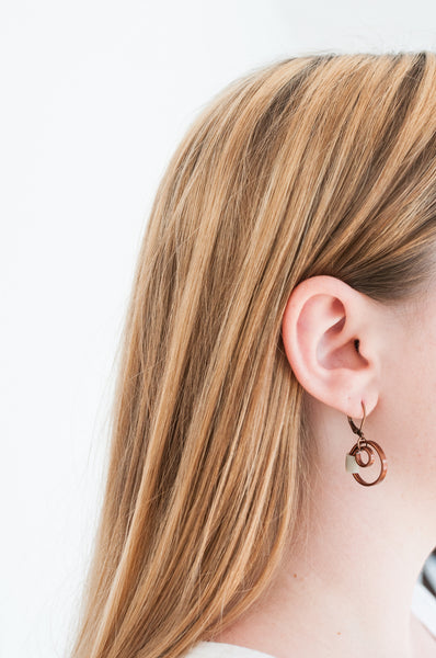 Isabelle is wearing Reel earrings in bronze and beige