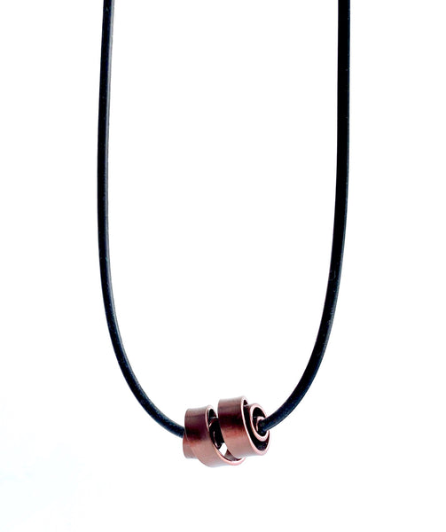 This Rubber Loopt necklace is in flat bronze coloured aluminum wire. It hangs on a rubber necklace with an interlocking closure. This piece comes in many variations.