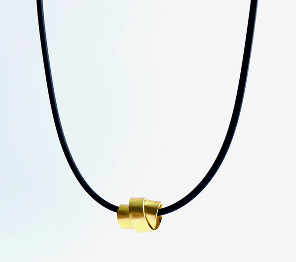 This Rubber Loopt necklace is in flat gold. Made of aluminum wire and hangs on a rubber necklace with an interlocking closure. This piece comes in many variations.