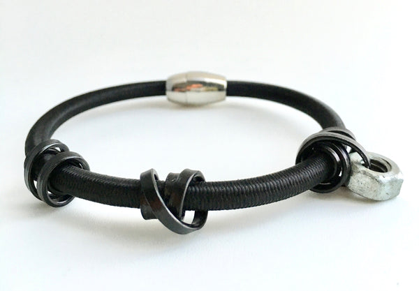 A Loopt bracelet in thin black aluminum coloured wire on heavy cord.