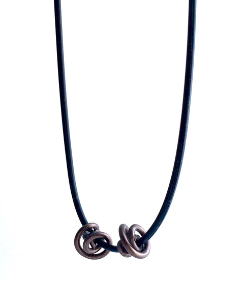 This Rubber Loopt necklace is in round bronze. Made of aluminum wire and hangs on a rubber necklace with an interlocking closure. This piece comes in many variations.