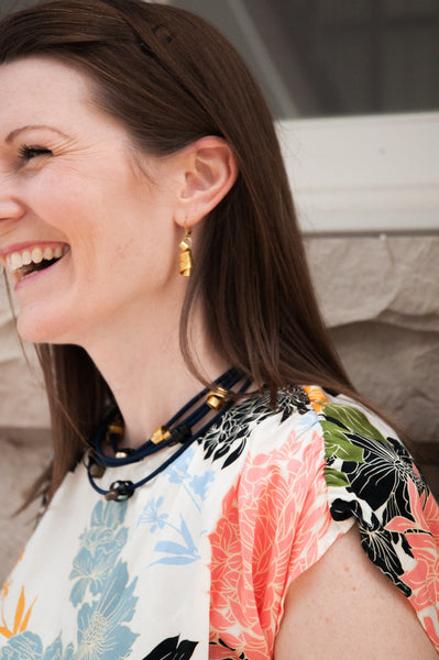 Sarah is wearing Flat Loopt Earrings in gold and a fine Loopt necklace/bracelet in navy and gold.