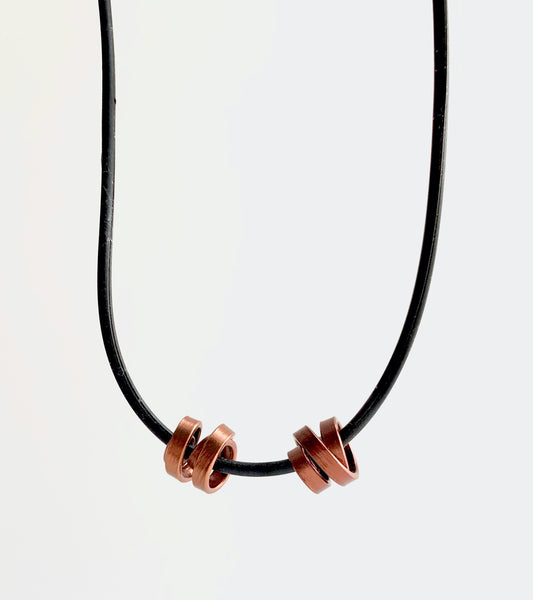 This Rubber Loopt necklace is in thin bronze. Made of aluminum wire and hangs on a rubber necklace with an interlocking closure. This piece comes in many variations.