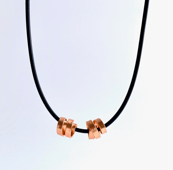This Rubber Loopt necklace is in thin copper. Made of aluminum wire and hangs on a rubber necklace with an interlocking closure. This piece comes in many variations.