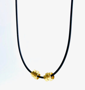 This Rubber Loopt necklace is in thin gold. Made of aluminum wire and hangs on a rubber necklace with an interlocking closure. This piece comes in many variations.