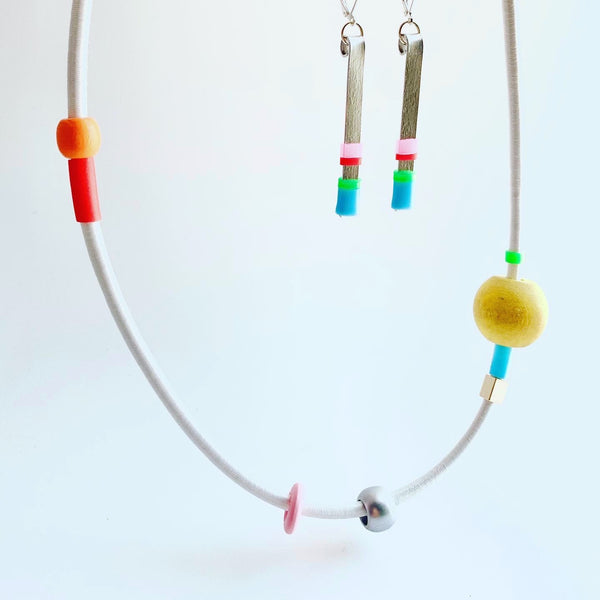 This piece is made with 5mm white shock cord and hangs 63cm long. It is paired here with matchstick earrings. Sold separately.