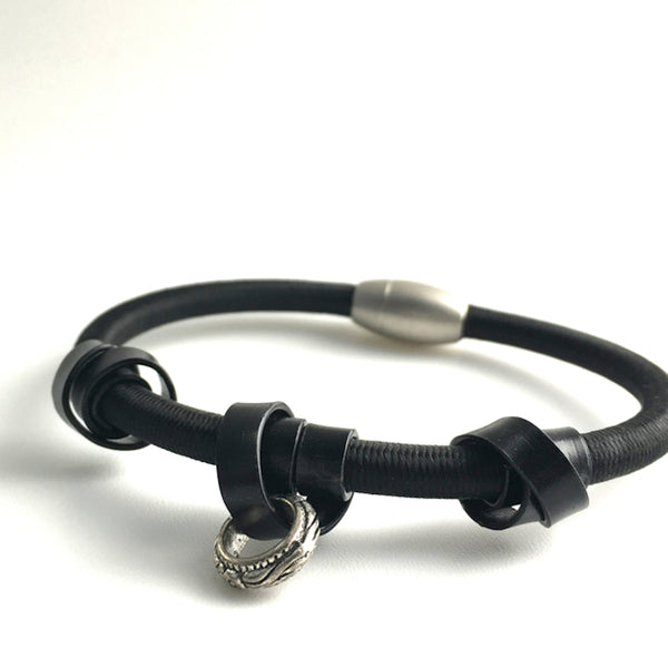 A Loopt bracelet in flat black aluminum coloured wire on heavy cord.
